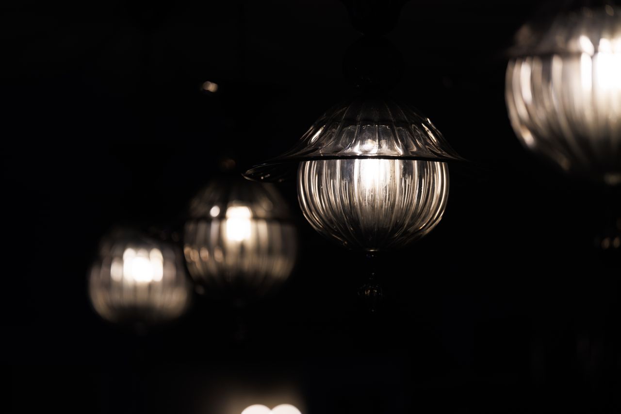 Close-up view of elegant glass pendant lights glowing in the dark, creating a moody atmosphere.
